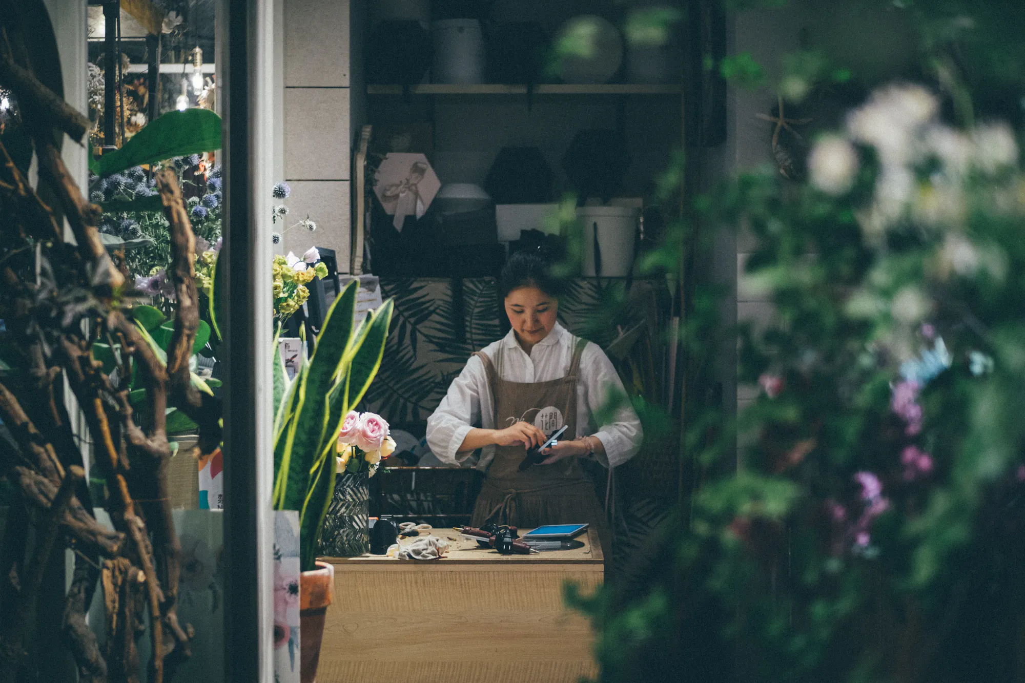 A florist working at the counter of her own flower shop