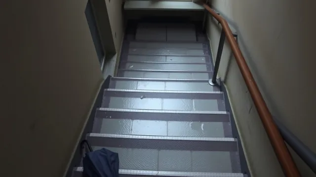 A wet exterior stairwell at an apartment building after rain, a dropped umbrella on one step